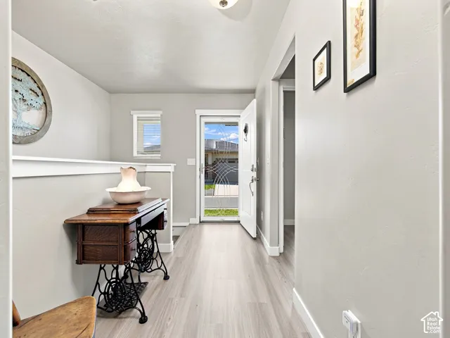 Entryway featuring wood-finish flooring, a white trim half-wall, and a white front door with decorative glass