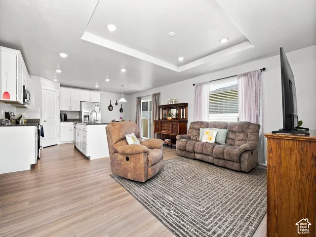 Open concept living area featuring a kitchen island, recessed lighting, wood-finish flooring, and a tray ceiling