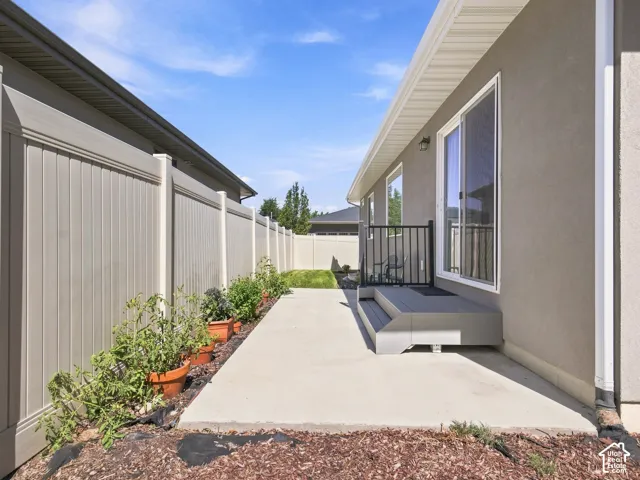 Stucco exterior with sliding glass door and side windows, complemented by a composite decking step and black metal railing