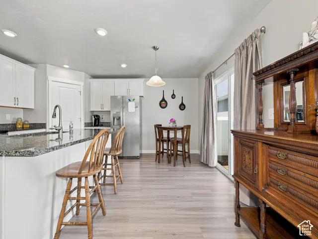Kitchen featuring white cabinetry, granite countertops, stainless steel refrigerator, and wood-finish flooring