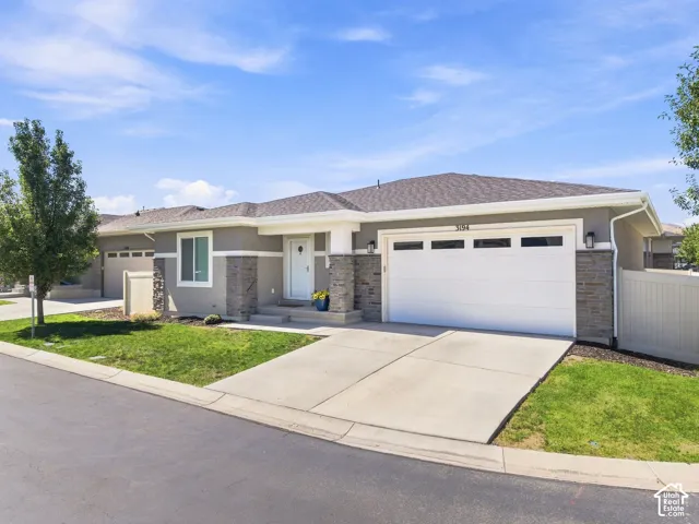 Contemporary stucco exterior with stone accents, an attached two-car garage, and a concrete driveway