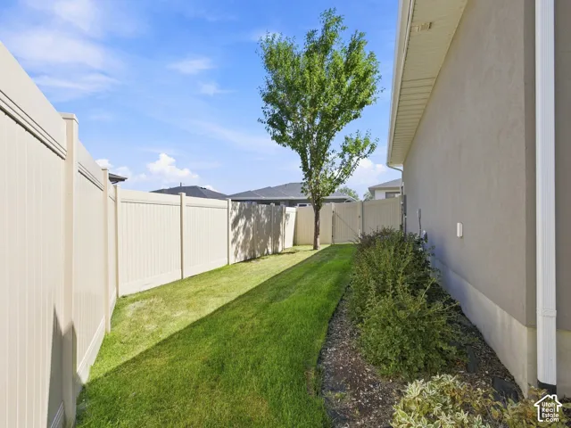 Private fenced yard featuring a manicured lawn, established shrubbery, and a mature tree