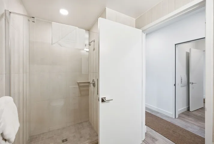 Shower enclosure with glass panel, tiled walls, and mosaic tile flooring