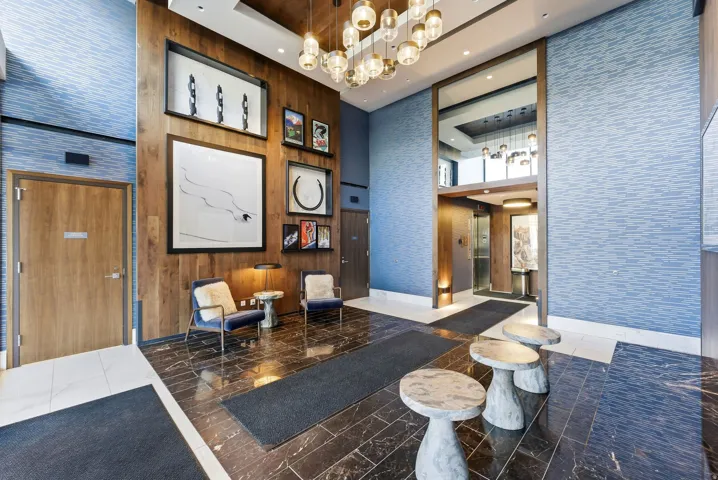 Entryway featuring a decorative ceiling fixture, wood-finish wall paneling, patterned wall covering, and polished dark tile flooring