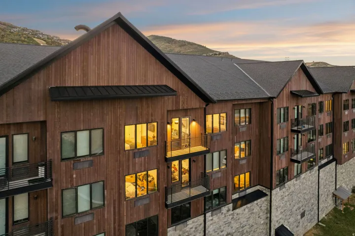 Multi-level exterior featuring wood-finish siding, a dark shingle roof, and stone facade