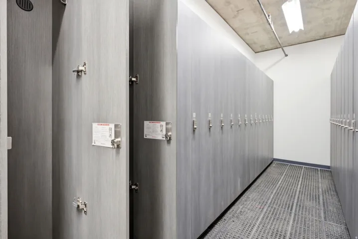 Locker room featuring rows of individual storage units, a textured flooring system, and exposed ceiling ductwork