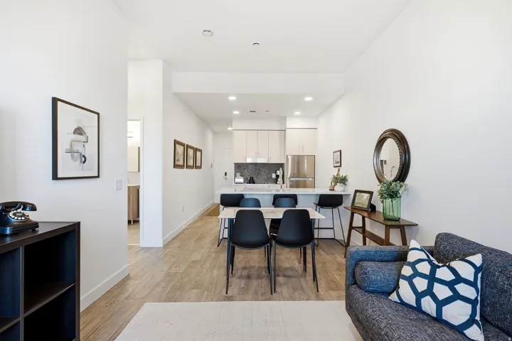 Open-concept living area with wood-finish flooring, recessed lighting, and a kitchen featuring stainless steel appliances, light-toned cabinetry, and a peninsula with seating