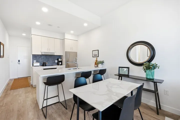 Kitchen featuring a large island with seating, integrated sink, wood-finish cabinetry, and a tile backsplash