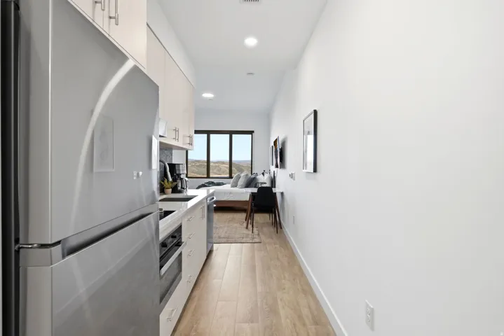 Integrated kitchen with stainless steel appliances, light wood-finish cabinetry, and recessed lighting