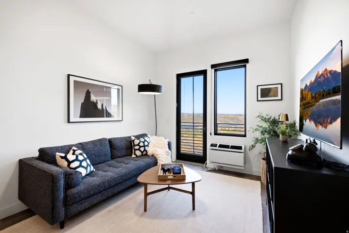 White walls with high ceilings, dark-framed glass door, and a dedicated wall-mounted climate control unit