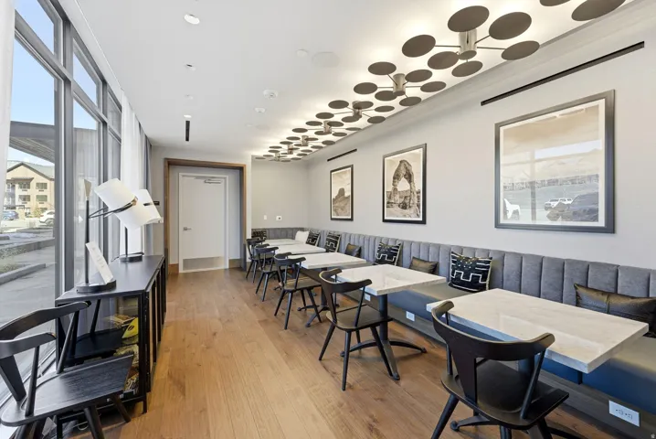 Full-height windows, wood-finish flooring, built-in upholstered banquette seating, a decorative ceiling light fixture, and recessed lighting