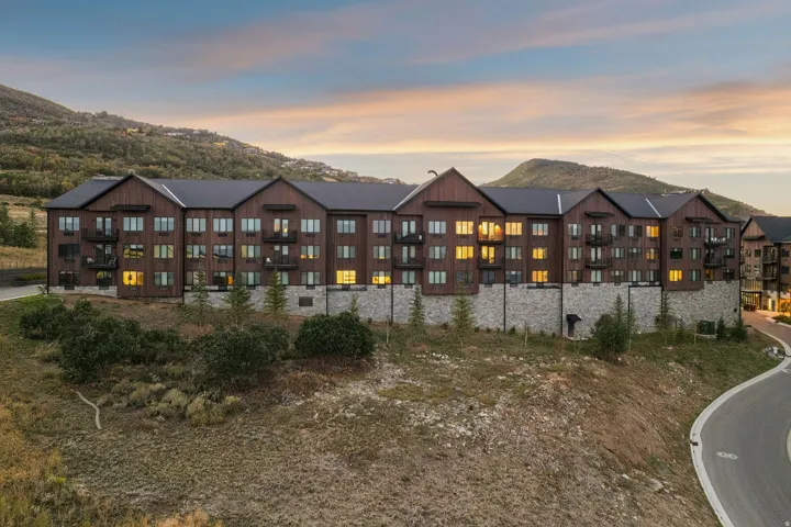Multi-level structure featuring a wood-finish facade, stone base, multiple balconies, and a dark shingle roof
