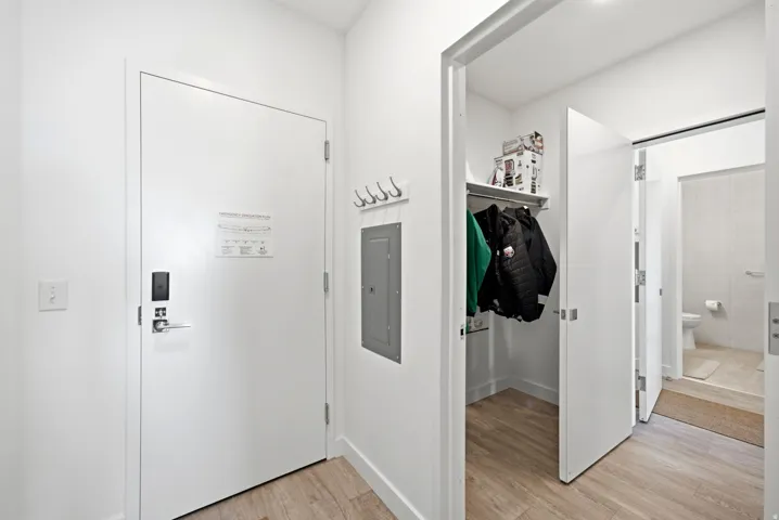Wood-finish flooring throughout, with a recessed coat closet featuring a built-in shelf