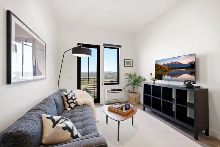 Wood-finish flooring, white walls, and an expansive window with a black frame