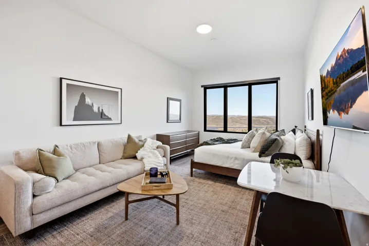 Spacious studio living area with high ceilings, recessed lighting, and a large window offering expansive outdoor scenery