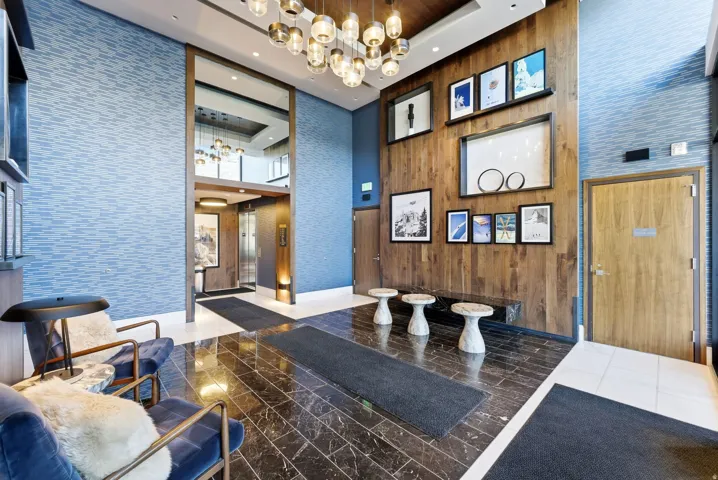 Lobby featuring wood paneling, patterned wall covering, a decorative chandelier, and polished dark tile flooring