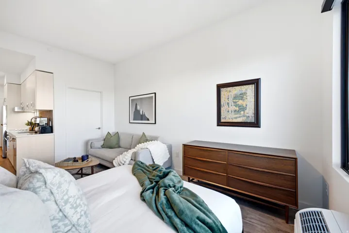 White walls, wood-finish flooring, light-toned cabinetry, stainless steel appliances, and a built-in kitchen counter