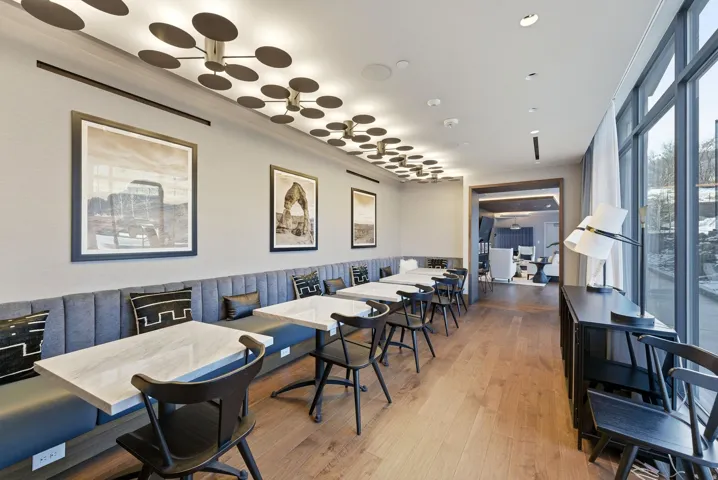 Wood-finish flooring, full-height window wall, built-in banquette seating, and unique ceiling light fixtures