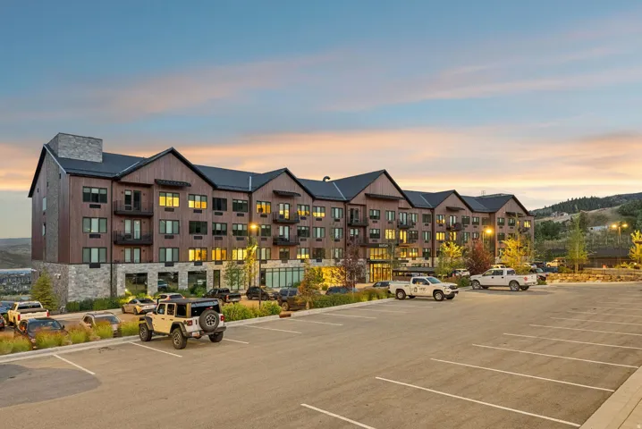 Multi-story building featuring stone and wood-finish siding, multiple balconies, and a sloped roofline