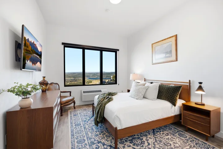Expansive window with natural scenery, wood-finish flooring, and white walls