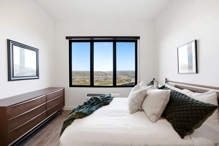 Large black-framed window, hard-surface flooring, white walls, and a low-profile heating unit