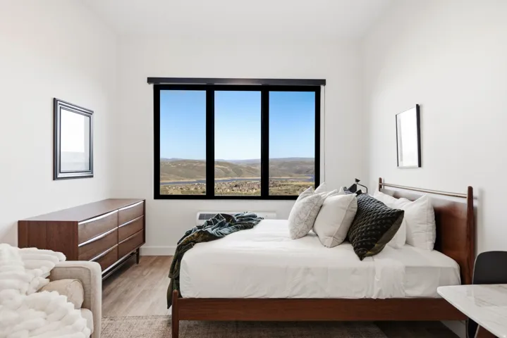 Expansive window with a wide frame, wood-finish flooring, and white walls