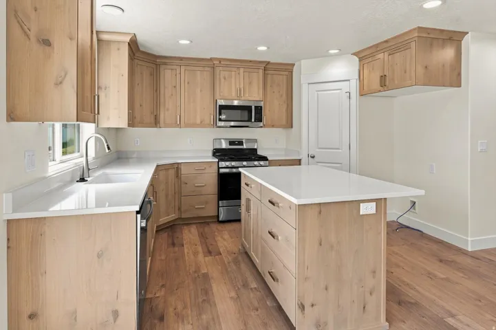 Kitchen featuring wood-finish cabinetry, white countertops, stainless steel appliances, and a central island