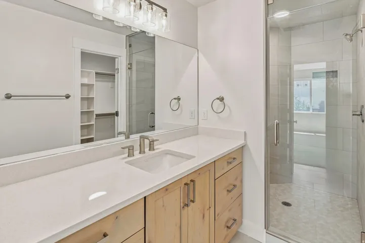 Wood-finish vanity with a single basin sink, white countertop, and brushed nickel hardware