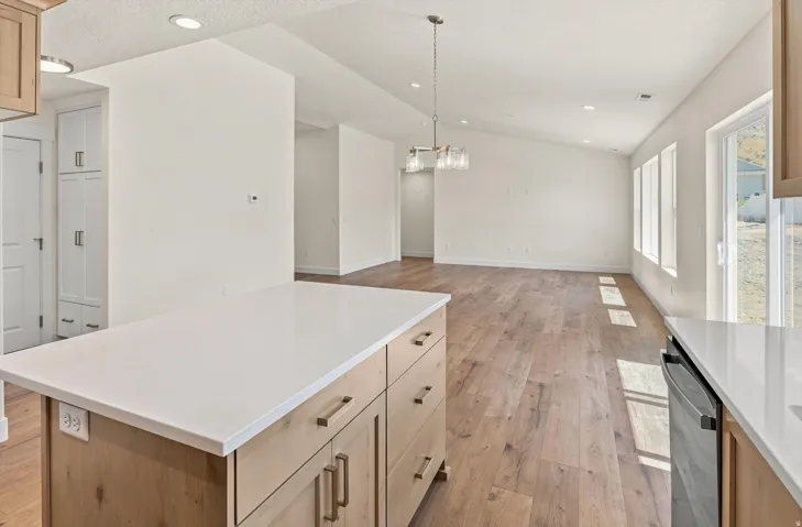 Open concept living area with wood-finish flooring, vaulted ceilings, and recessed lighting