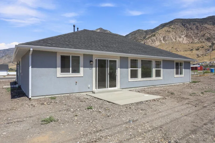 Stucco exterior with multiple windows, a sliding glass door, and a concrete patio