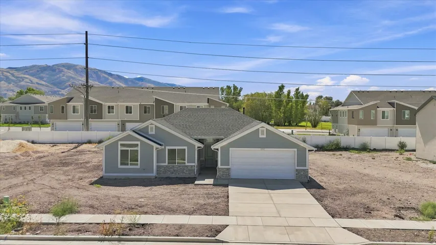 Single-story residence featuring a light gray exterior with stone accents, a two-car garage, and a concrete driveway