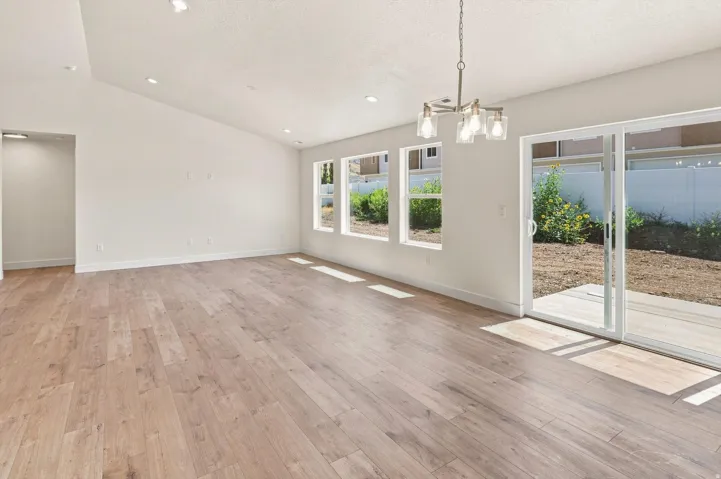 Vaulted ceiling, wood-finish flooring, recessed lighting, multiple windows, and sliding glass door to exterior