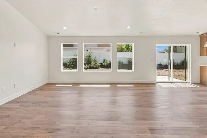 Open-concept living area featuring wood-finish flooring, recessed lighting, multiple windows, and a sliding glass door