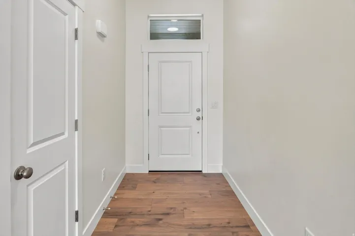 Wood-finish flooring, white paneled doors, and a transom window above the entry