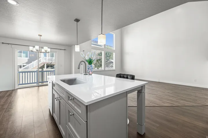 Kitchen island with a stainless steel sink, light-colored countertop, and grey cabinetry