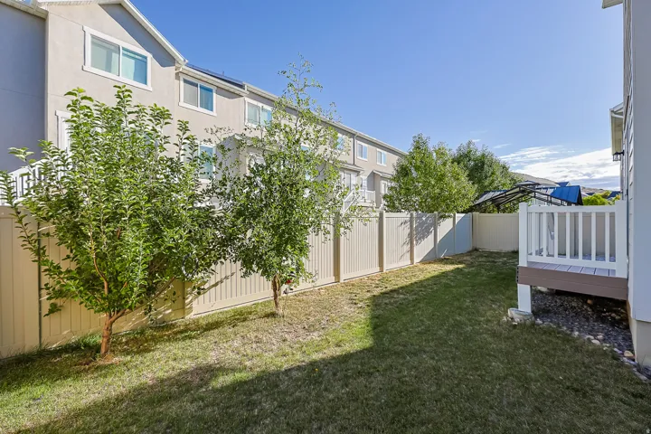 Expansive backyard featuring a fenced perimeter, established trees, and a raised wood-finish deck with white railings