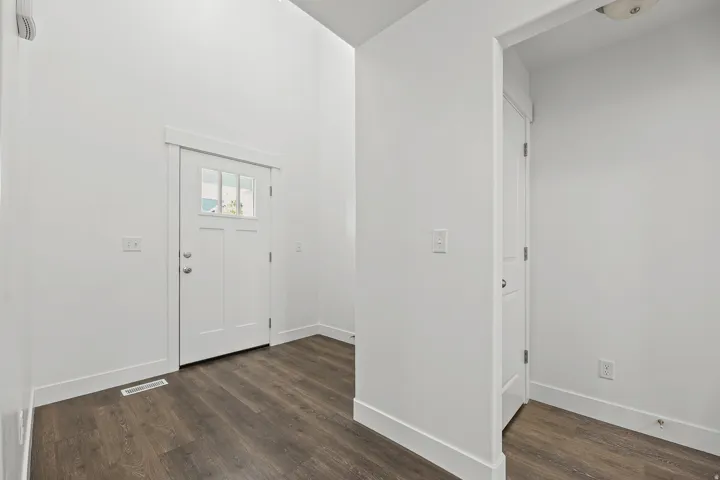 Entryway featuring a white paneled door with glass inserts, dark wood-finish flooring, and white trim