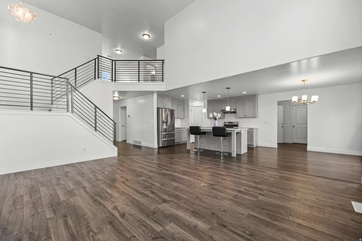 Vaulted ceilings, wood-finish flooring, and a modern horizontal bar railing staircase