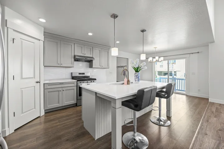 Kitchen featuring light gray cabinetry, white countertops, a white subway tile backsplash, and wood-finish flooring