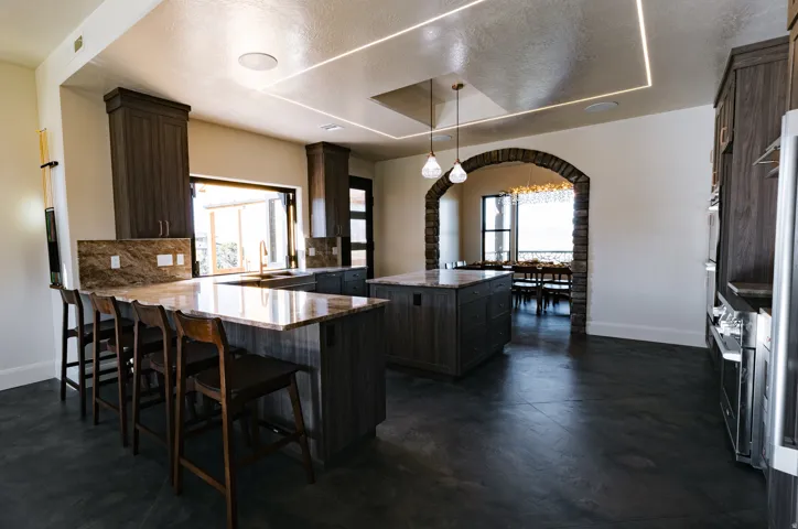 Kitchen featuring dark wood-finish cabinetry, granite countertops, a large center island, and a stone archway
