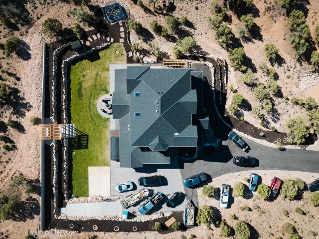Expansive property featuring a dark-toned multi-gabled roofline, concrete driveway, and a large manicured lawn