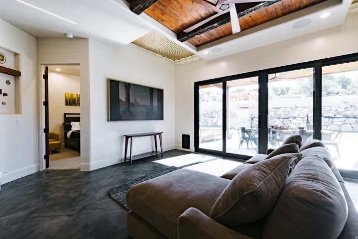 Concrete-finish flooring, exposed wood beam ceiling, recessed lighting, and expansive glass sliding doors