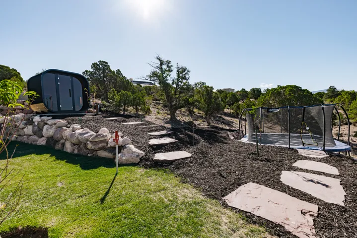 Terraced yard featuring a rock retaining wall, a modern outdoor pod, a putting green, and stone slab steps