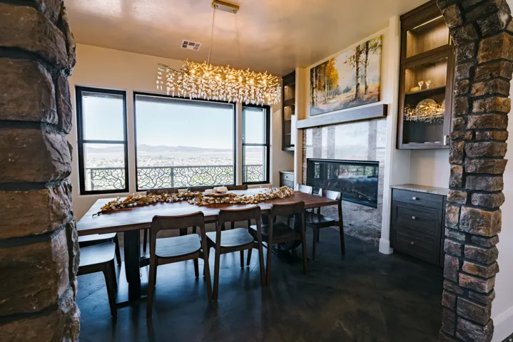 Stone archway leading into a dining area with large windows, a linear fireplace, built-in cabinetry, and a tiered chandelier