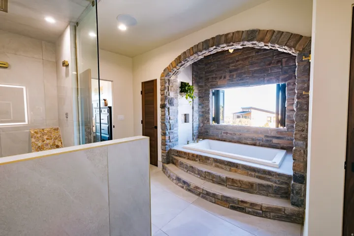 Stone archway framing a built-in soaking tub with stone steps