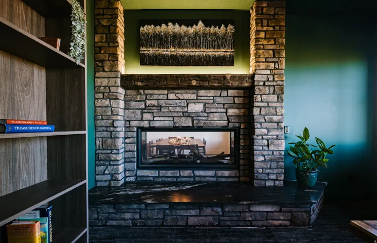 Stone-faced fireplace with a built-in firebox, wood mantel, and stone hearth