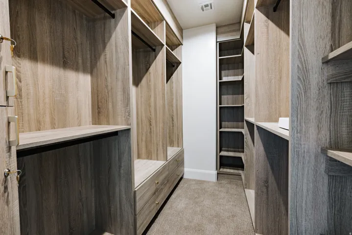Custom closet system featuring wood-finish shelving, integrated drawers, hanging rods, and recessed lighting