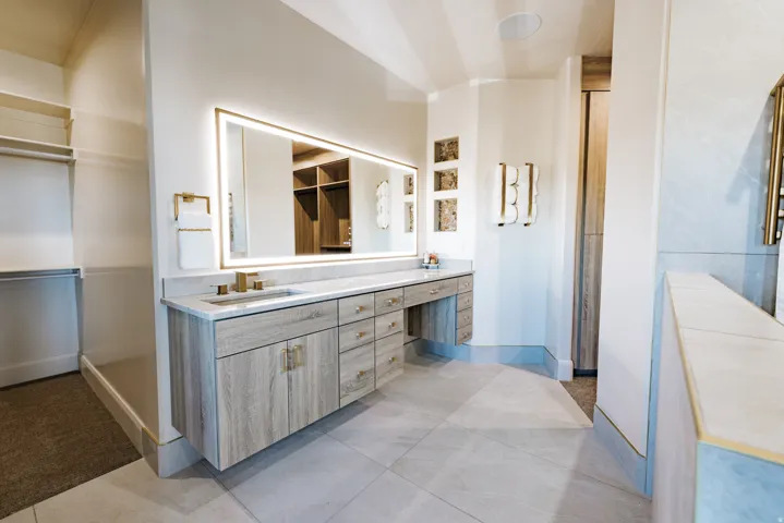 Floating vanity with wood-finish cabinetry, integrated lighting mirror, dual sinks, and tile flooring