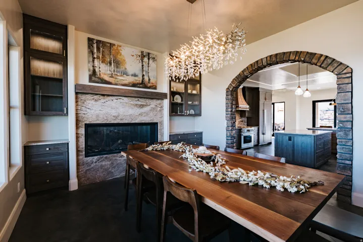 Stone-clad archway leading to the kitchen, a built-in fireplace with a stone surround, and integrated cabinetry with glass-front uppers