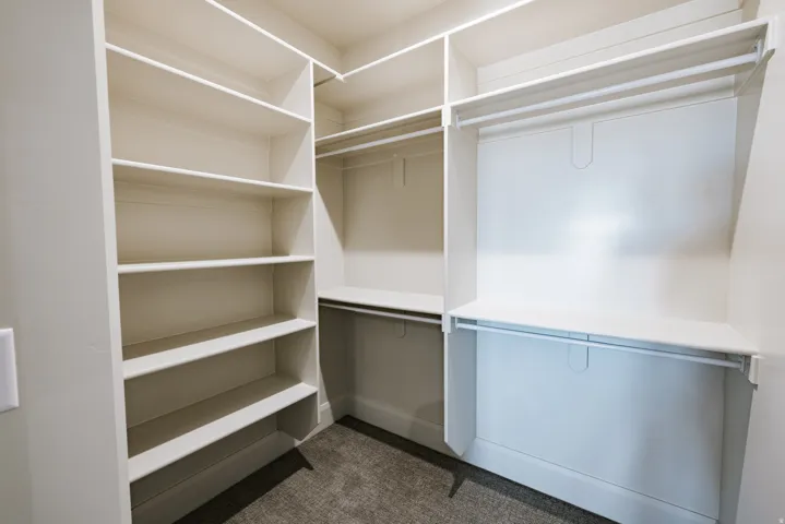 Built-in closet system featuring multiple shelves and hanging rods, complemented by carpet flooring